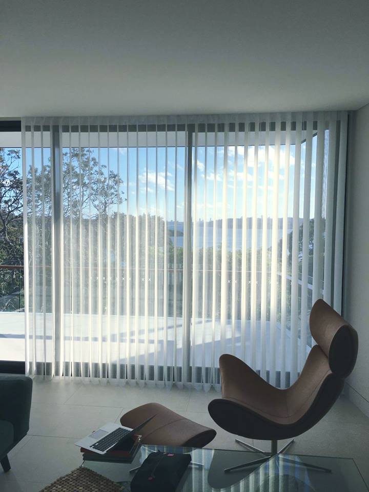 Office space with vertical blinds on large windows. Modern chair, laptop, and glass table. Turn ordinary room into office concept.