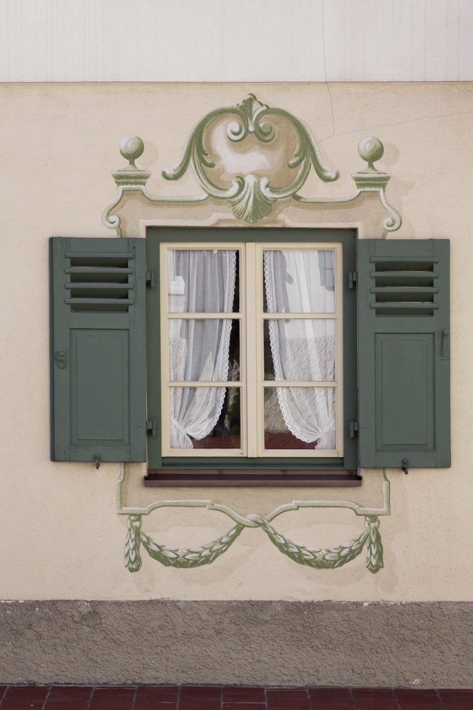 Window with timber shutters and decorative paint. Timber shutters add character to this seaside property, enhancing its charm and curb appeal.