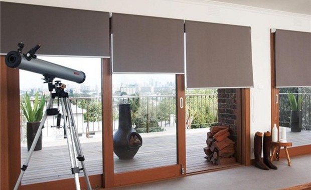 Interior with soft, subtle colored roller blinds, telescope, and outdoor view. Window treatment trends bring nature indoors.