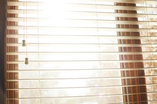 Close-up of custom-made blinds in Perth, showcasing horizontal slats filtering sunlight. Window covering detail, light control, and interior design.