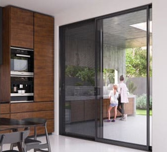 Modern kitchen interior with wood cabinets, built-in appliances, and a large sliding glass door. Outside, a mother and child are visible. Community.